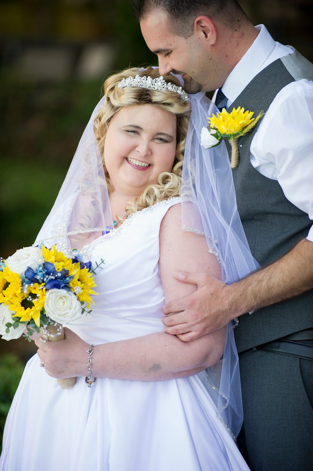 Outdoor Bride and Groom Portrait, Bride in Satin V-Neck Ballgown Wedding Dress with Straps and Rhinestone Beading, Beaded Headband and Veil with Yellow Sunflower, White Roses, Blue and Greenery Floral Bouquet, Groom in Grey Vest and Yellow Sunflower Boutonneire | Tampa Bay Photographer Andi Diamond Photography