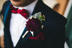 Groom Wedding Portrait with Plum Floral Boutonniere, Red Bowtie and Red Silk Pocket Square