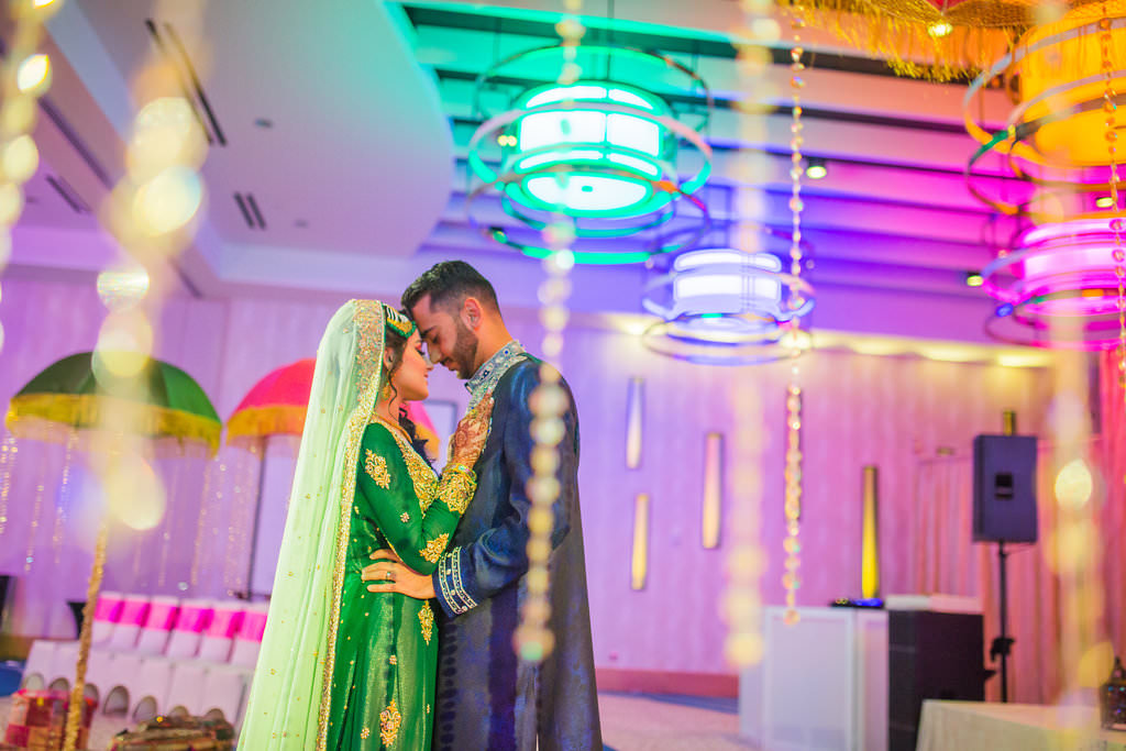 Glamorous Indian Wedding, Bride in Traditional Green and Gold Sari Dancing with Groom in Hotel Ballroom and Hanging Crystals | Tampa Bay Wedding Venue Wyndham Grand Clearwater Beach