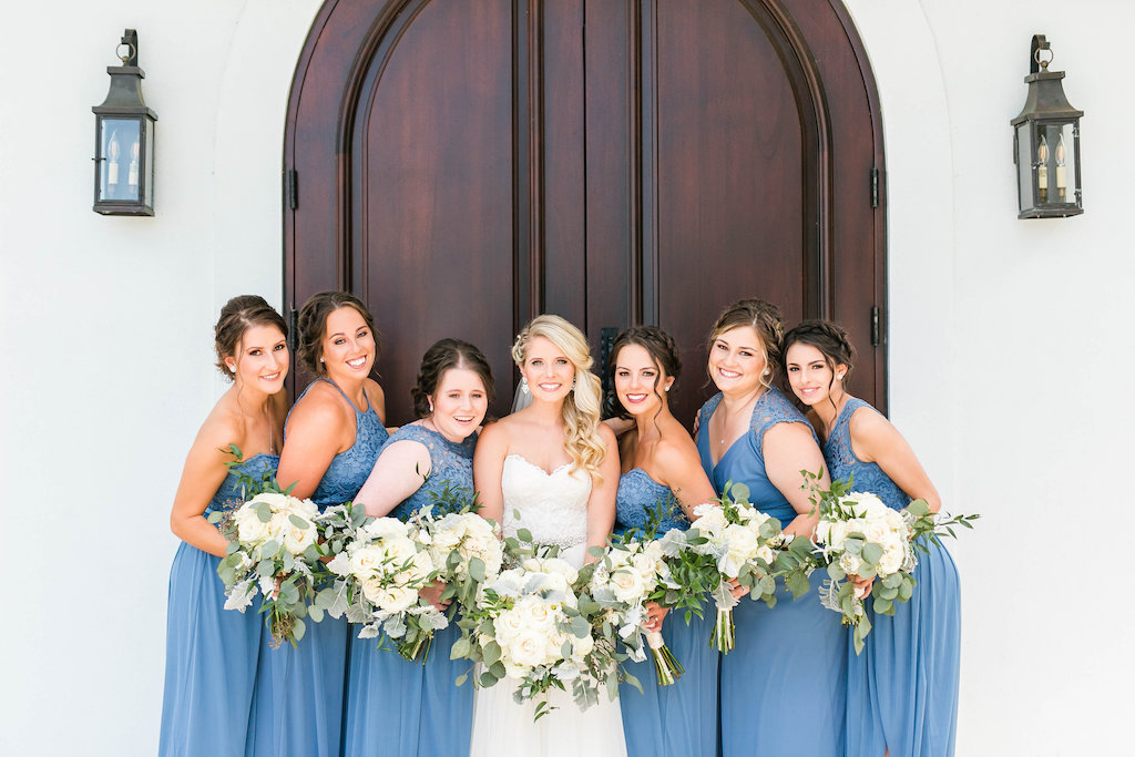 Bride and Bridesmaids Wedding Portrait, Bride in Sweetheart Strapless Lace A-Line Wedding Dress, Bridesmaids in Dusty Blue Mismatched Style Dresses with White/Ivory and Greenery Floral Bouquets | Tampa Bay Hair and Makeup Femme Akoi | Clearwater Wedding Ceremony Venue Harborside Chapel