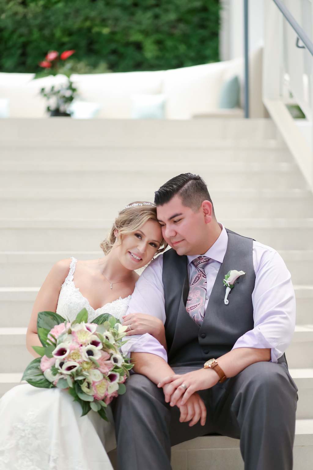 Outdoor Staircase Bride and Groom Wedding Portrain, Bride in Tank Top Lace and V Neckline Wedding Dress, White, Pink and Green Palm Leave Floral Bouquet, Groom in Grey Tuxedo Vest, Paisley Print Tie | Tampa Bay Wedding Photographer Lifelong Photography Studios | Wedding Venue Hilton Clearwater Beach