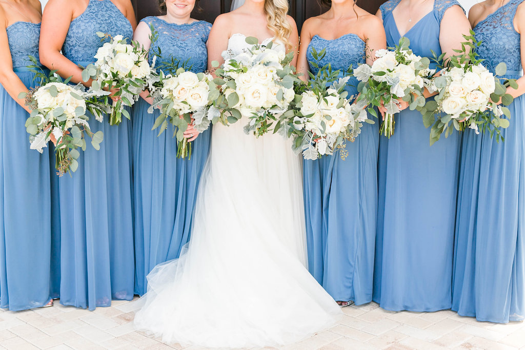 Bride and Bridesmaids Wedding Portrait, Bride in Sweetheart Strapless Lace A-Line Wedding Dress, Bridesmaids in Dusty Blue Mismatched Style Dresses with White/Ivory and Greenery Floral Bouquets | Tampa Bay Hair and Makeup Femme Akoi | Clearwater Wedding Ceremony Venue Harborside Chapel