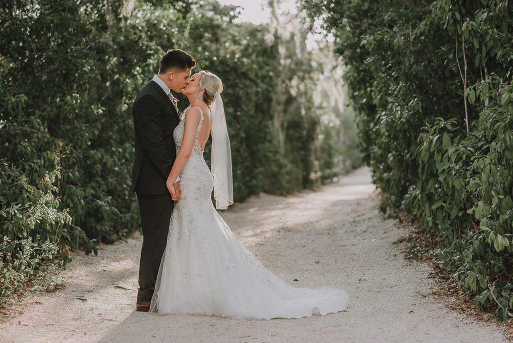 Bride and Groom Garden Wedding Portrait, Bride in Fit and Flare, Floral Lace Embellished and Rhinestone Low Back Wedding Dress with Straps and Veil | Tampa Bay Bridal Wedding Dresses Truly Forever Bridal | Sarasota Wedding Venue Historic Spanish Point