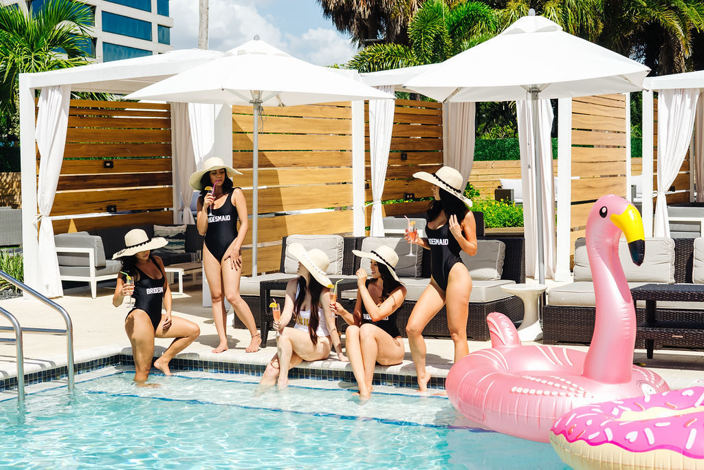 Tampa Bay Bachelorette Party Lounging By Hotel Pool in Custom Black and White Bathing Suits and Personalized Hats | Tampa Bay Wedding Venue The Godfrey Hotel | Photographer Grind and Press Photography | Bachelorette Attire Isabel O'Neil Bridal | Hair and Makeup Michele Renee the Studio
