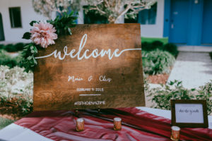 Wedding Ceremony Wooden Welcome Sign on Table with Burgundy Red Table Runner and Gold Candle Votives