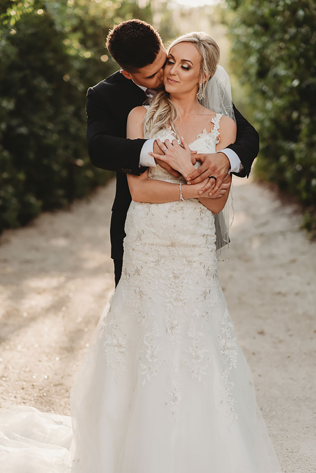 Bride and Groom Outdoor Garden Wedding Portrait, Bride in Fit and Flare, Floral Lace Embellished and Rhinestone V Neck Wedding Dress with Straps and Veil | Tampa Bay Bridal Wedding Dresses Truly Forever Bridal | Sarasota Wedding Venue Historic Spanish Point