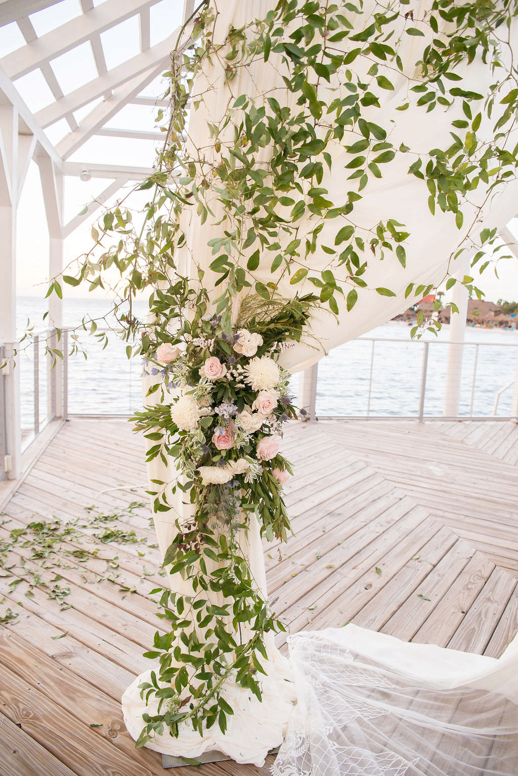 Florida Outdoor Waterfront Wedding Ceremony Decor, Arch with White Linen Drapery and Greenery Leaves and Ivory and Blush Pink Florals | Tampa Wedding Photographer Kristen Marie Photography | Tampa Wedding Venue The Godfrey | Draping Rentals Gabro Event Services