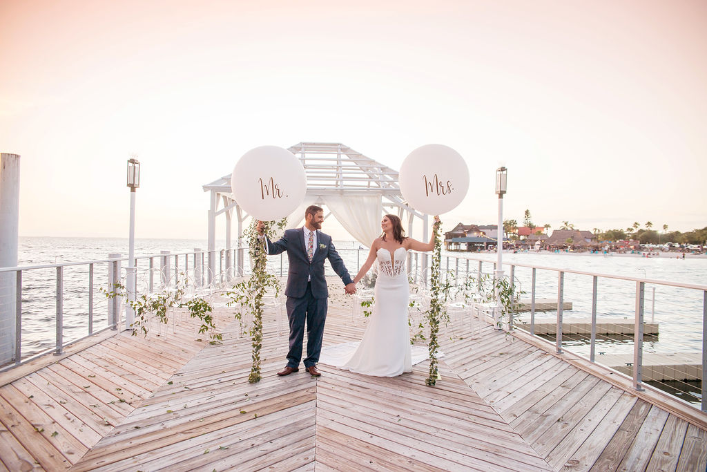 Florida Outdoor Waterfront Bride and Groom Wedding Ceremony Portrait, Bride and Groom Holding Custom White Mr. and Mrs. Large Oversized White Balloons with Garland String | Tampa Wedding Photographer Kristen Marie Photography | Tampa Venue The Godfrey Instagram
