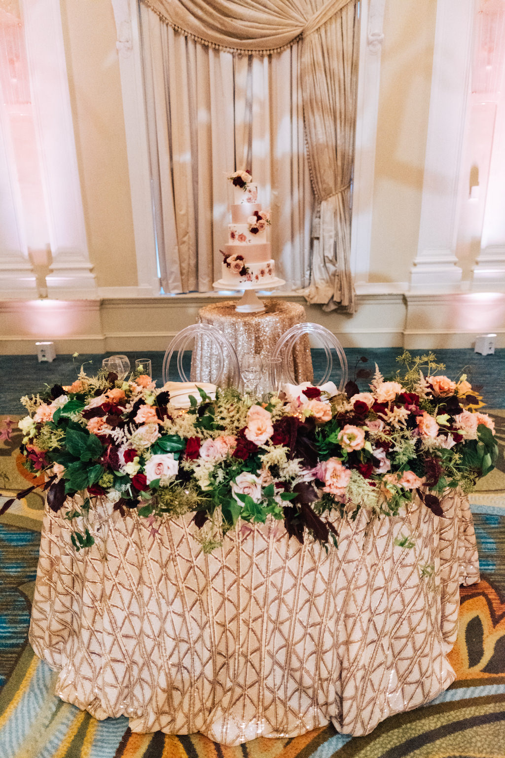 Elegant, Romantic Hotel Wedding Reception Decor, Sweetheart Table with Gold Tablecloth, Burgundy, Dusty Rose, Red, and Greenery Floral Garland, Clear Acrylic Chairs | St. Petersburg Hotel Wedding Venue The Vinoy Renaissance | Tampa Bay Wedding Planner Parties A'la Carte