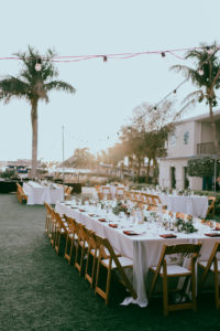 Outdoor Garden Lawn Wedding Reception Decor, Long Feasting Table, White Tablecloths, Burgundy Linens, Wooden Folding Chairs with White Cushions, Low Floral Centerpieces | St. Petersburg Wedding Venue Postcard Inn on the Beach