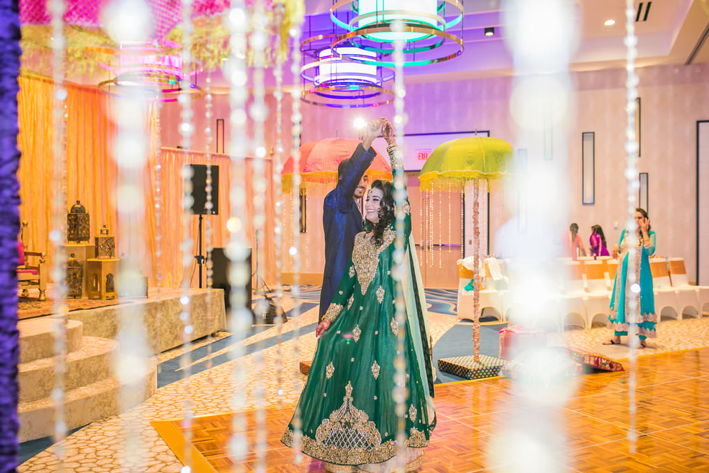 Glamorous Indian Wedding, Bride in Traditional Green and Gold Sari Dancing with Groom in Hotel Ballroom and Hanging Crystals | Tampa Bay Wedding Venue Wyndham Grand Clearwater Beach
