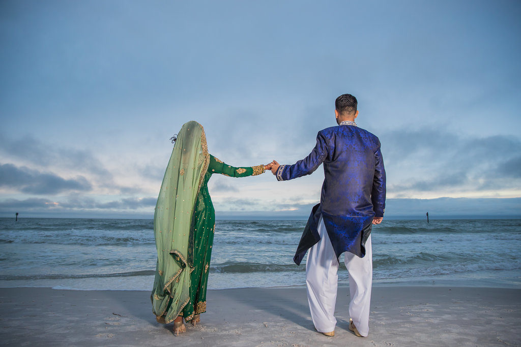 Indian Bride and Groom on Beach Wedding Portrait, Bride in Traditional Green and Gold Sari, Groom in Traditional Blue and White Attire | Tampa Bay Wedding Venue Wyndham Grand Clearwater Beach