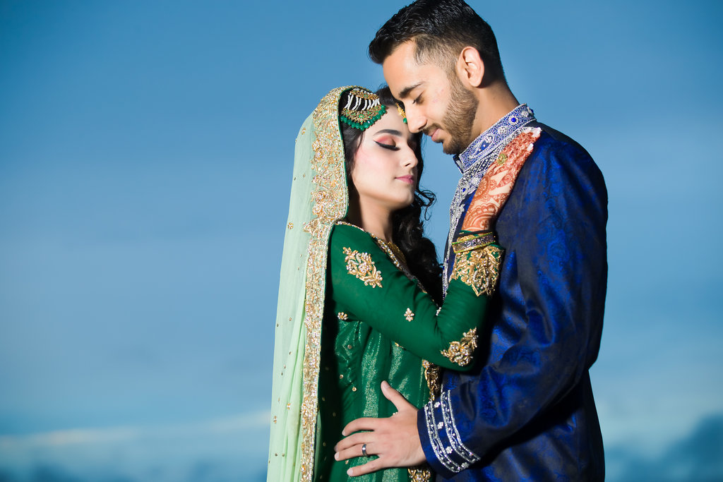 Indian Bride and Groom on Beach Wedding Portrait, Bride in Traditional Green and Gold Sari with Henna Tattoo, Groom in Traditional Blue and White Attire | Tampa Bay Wedding Venue Wyndham Grand Clearwater Beach
