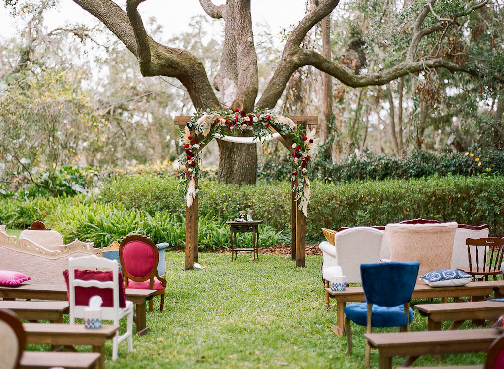 Boho Chic Inspired Outdoor Lakeland Florida Wedding Ceremony Decor, Wooden Arch with Red, Ivory, Pink and Greenery Organic Floral Decor, Vintage Chairs, Benches and Loveseats