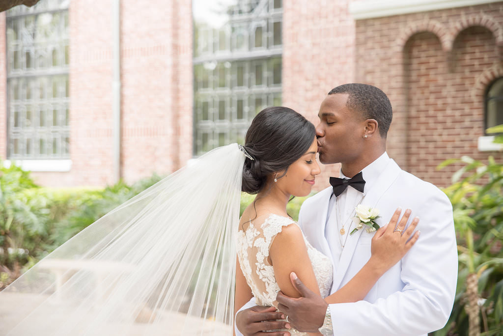 Florida Bride and Groom Outdoor Wedding Portrait, Bride in Fitted Lace and Illusion Cap Sleeve Wedding Dress with Cathedral Length Veil, Groom in White Tuxedo | Tampa Bay Wedding Photographer Kristen Marie Photography | Tamp Wedding Venue St. Paul's Catholic Church