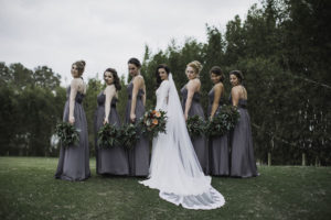 Outdoor Florida Bride and Bridesmaids Wedding Portrait, Bride in Crepe and Lace Mermaid Long Sleeve Wedding Dress with Cathedral Veil, Bridesmaids in Matching Halter Top Grey Long Dresses | Waterfront Venue Isla Del Sol Yacht and Country Club