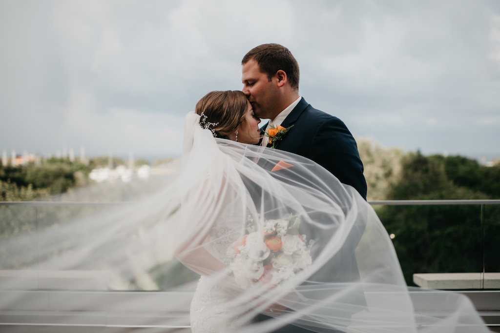 Creative Outdoor Bride and Groom Wedding Portrait with Veil Blowing in Wind