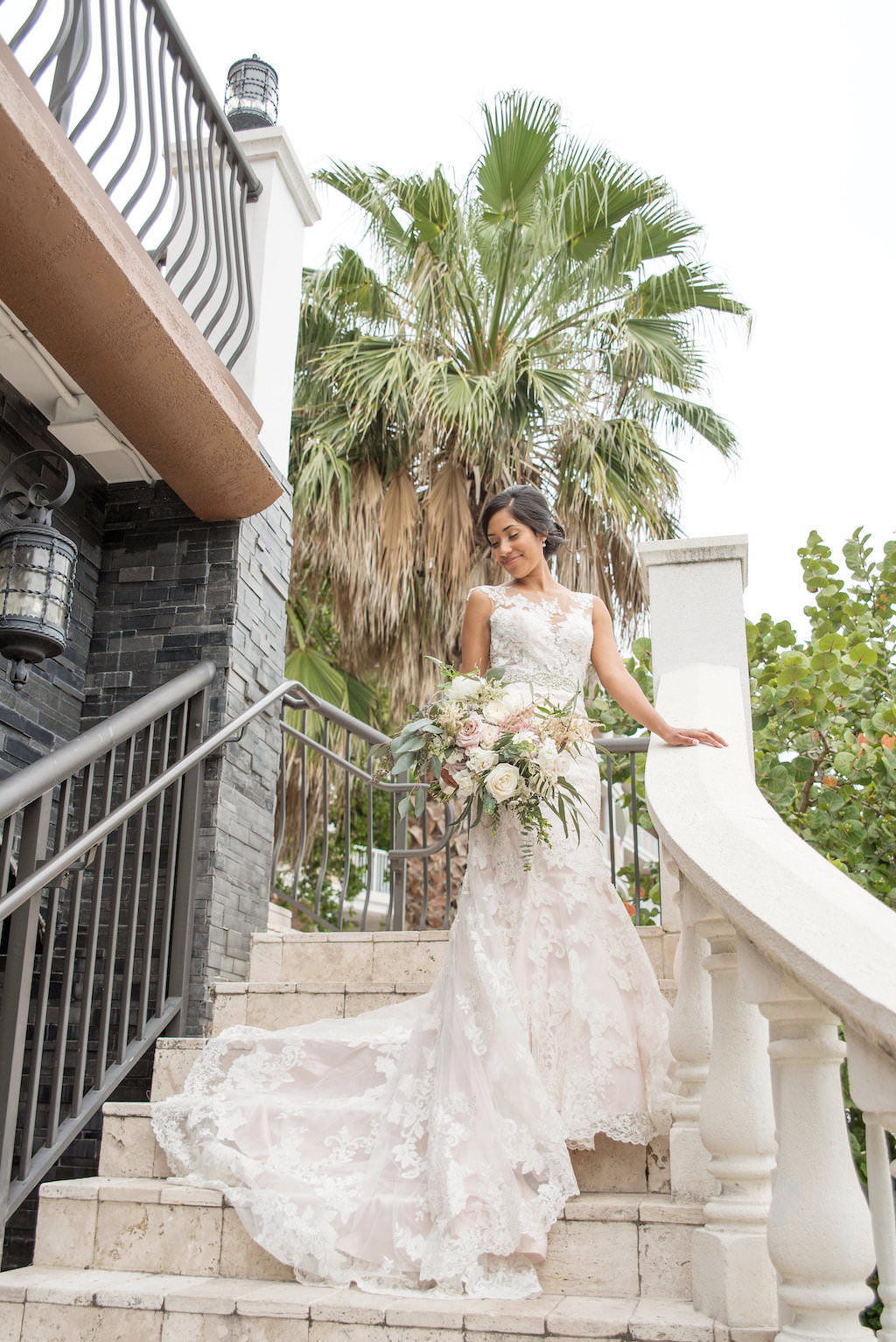 Florida Bride Outdoor Wedding Portrait on Staircase in Fitted Allure Lace and Illusion Cap Sleeve Wedding Dress with Organic Garden Inspired Floral Bouquet | Tampa Bay Wedding Photographer Kristen Marie Photography
