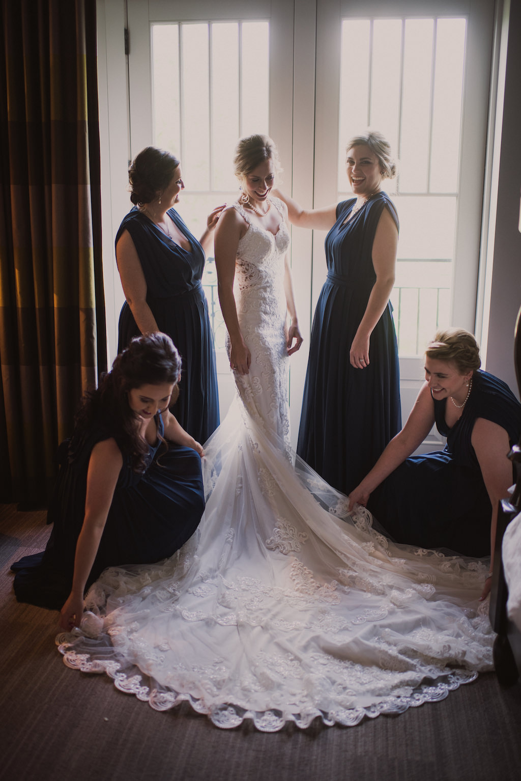 Bride and Bridesmaids Getting Ready Wedding Portrait, Bride in Lace V-Neckline with Lace Straps Essense of Australia Wedding Dress, Bridesmaids in Navy Blue Long Matching Dresses