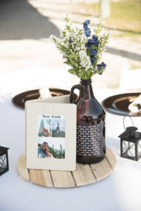 Rustic Wedding Reception Decor, Round Wooden Tray, Photo of Couple on Wooden Frame, Beer Growler Glass Bottle with White, Blue and Greenery Floral Centerpiece | Tampa Bay Florist Cotton and Magnolia