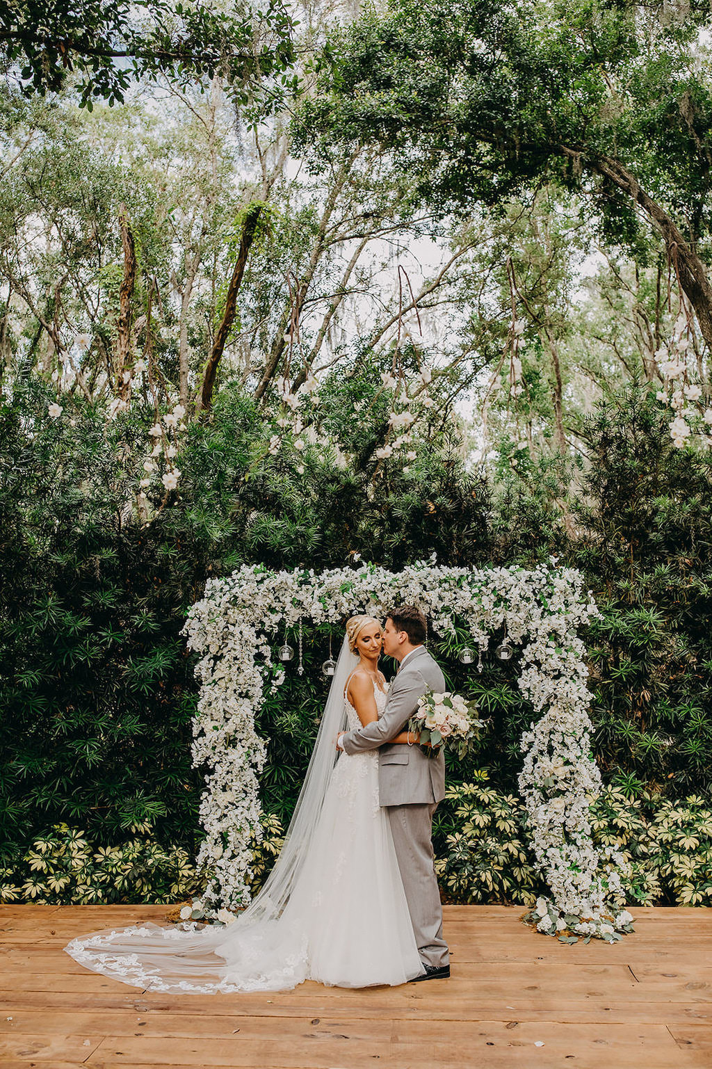 Florida Bride and Groom Wedding Portrait at Outdoor Rustic Inspired Wedding, White and Greenery Floral Arch with Hanging Glass Bulbs | Lakeland Rustic Wedding Venue The Prairie Glenn Barn at Gable Oaks Ranch