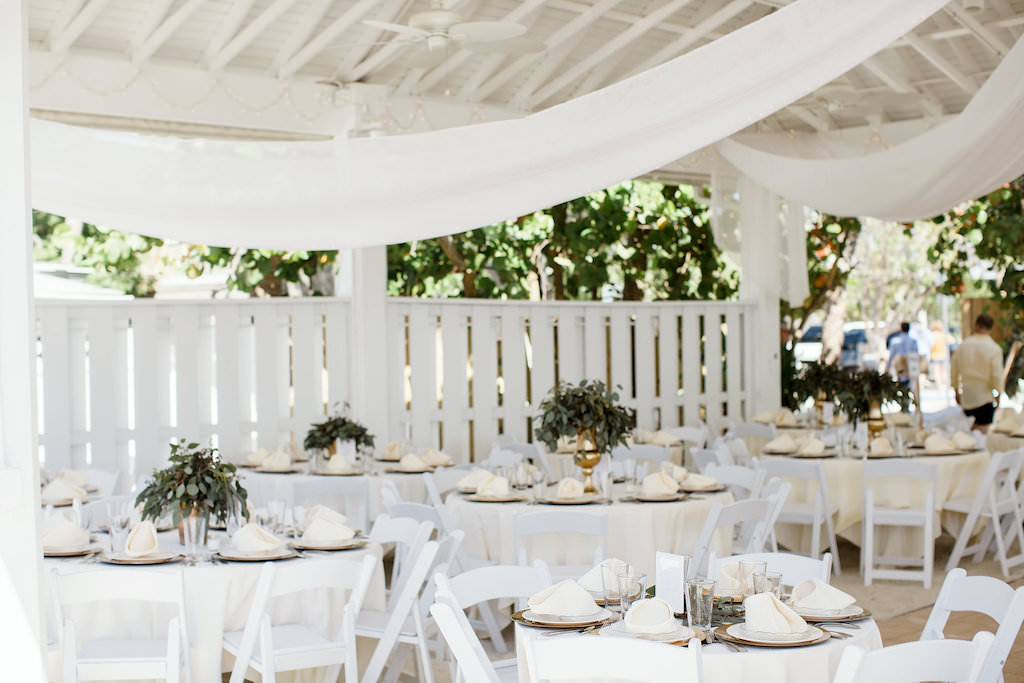 Tropical Inspired Wedding Reception Decor, Round Tables with White Tablecloths, Low Gold Vases with Greenery Centerpieces | Sarasota Beachfront Wedding Venue Sandbar Waterfront Restaurant