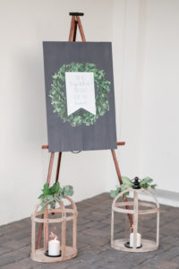 Black Wooden Panel with Painted Wreath and Personalize Sign, White Wash Wooden Lanterns with Candle and Greenery Decor | Tampa Bay Wedding Photographer Lifelong Photography Studio | Wedding Planner Love Lee Lane