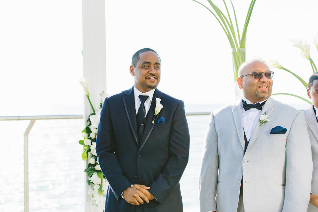Florida Groom Watching Bride Walking Down the Aisle in Black Tuxedo and Lily Boutonniere | Tampa Bay Wedding Photographer Kera Photography | Clearwater Beach Wedding Venue Opal Sands Resort