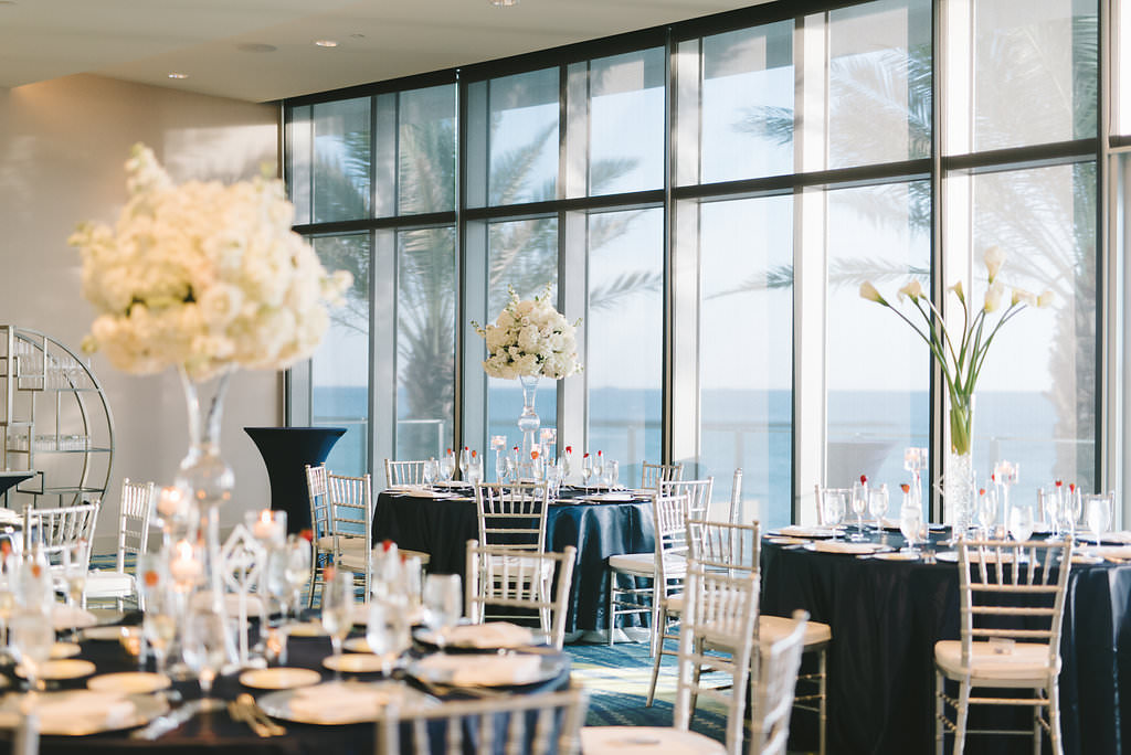 Ballroom Modern Elegant Wedding Reception Decor, Round Tables with Navy Blue Tablecloths, Silver Chiavari Chairs, Tall White Floral Arrangements on Clear Glass Vases Centerpieces | Tampa Bay Wedding Photographer Kera Photography | Clearwater Beach Wedding Venue Opal Sands Resort