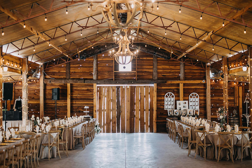 Florida Rustic Barn Inspired Wedding Reception, Long Feasting Tables with Wooden Chiavari Chairs | Lakeland Rustic Barn Wedding Venue Florida Rustic Inspired Wedding Reception Decor, Metal White Wagon, Wooden Barrel Welcome Table with Pictures and Window Pane Seating Chart | Lakeland Rustic Barn Wedding Venue Florida Outdoor Rustic Inspired Bride and Groom Wedding Portrait | Lakeland Rustic Wedding Venue The Prairie Glenn Barn at Gable Oaks Ranch