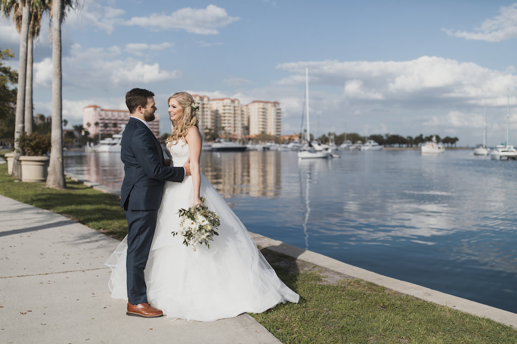 Outdoor Downtown St. Pete Waterfront Florida Bride and Groom Wedding Portrait, Bride in Strapless Hayley Paige Chantelle Gown, Ivory Tulle Skirt Ball Gown with Lace Corset Bodice, White and Greenery Floral Bouquet, Groom in Navy Blue Suit | Tampa Bay Wedding Hair and Makeup Artist Michele Renee the Studio