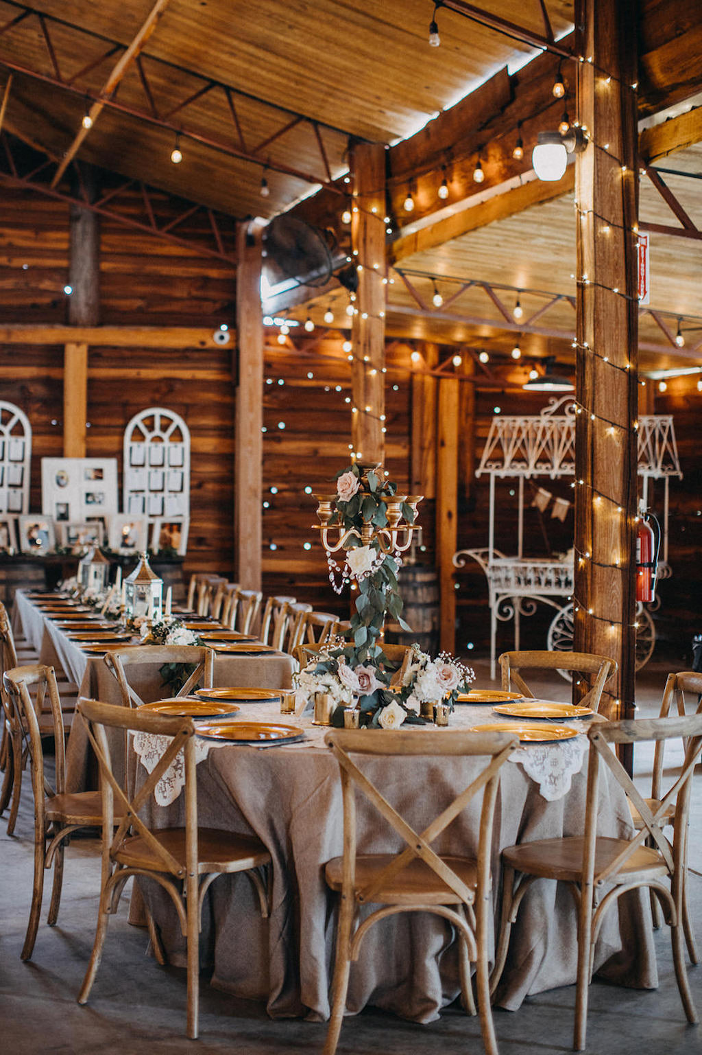 Florida Rustic Barn Inspired Wedding Reception Decor, Round Table with Tan Tablecloths, Gold Chargers, Wooden Chiavari Chairs, Tall Gold Candlestick Holder with Greenery and Rose Floral Centerpiece | Lakeland Rustic Barn Wedding Venue Florida Rustic Barn Inspired Wedding Reception, Long Feasting Tables with Wooden Chiavari Chairs | Lakeland Rustic Barn Wedding Venue Florida Rustic Inspired Wedding Reception Decor, Metal White Wagon, Wooden Barrel Welcome Table with Pictures and Window Pane Seating Chart | Lakeland Rustic Barn Wedding Venue Florida Outdoor Rustic Inspired Bride and Groom Wedding Portrait | Lakeland Rustic Wedding Venue The Prairie Glenn Barn at Gable Oaks Ranch