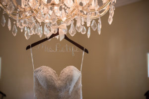Sweetheart Stella York Strapless Lace and Rhinestone Embellished Wedding Dress on Personalized Wire and Wooden Hanger Hanging on Chandelier | Sarasota Wedding Photographer Cat Pennenga Photography