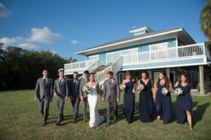 Florida Outdoor Bride, Groom and Wedding Party Portrait, Bridesmaids in Navy Blue Mismatched Style Long Dresses, Groomsmen in Grey Suits, Bride in Fitted Spaghetti Strap V Neckline Lace Wedding Dress | Waterfront Wedding Venue Tampa Bay Watch
