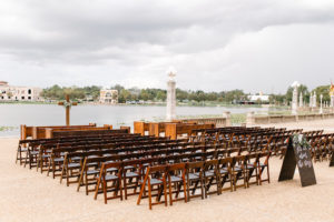 Tampa Bay Lakefront Wedding Ceremony Decor, Wooden Folding Chairs, Custom Folding Wooden Signs with Greenery Garland, Wooden Cross | Lakeland Wedding Venue Lake Mirror Amphitheater | Wedding Planner Love Lee Lane | Rentals A Chair Affair