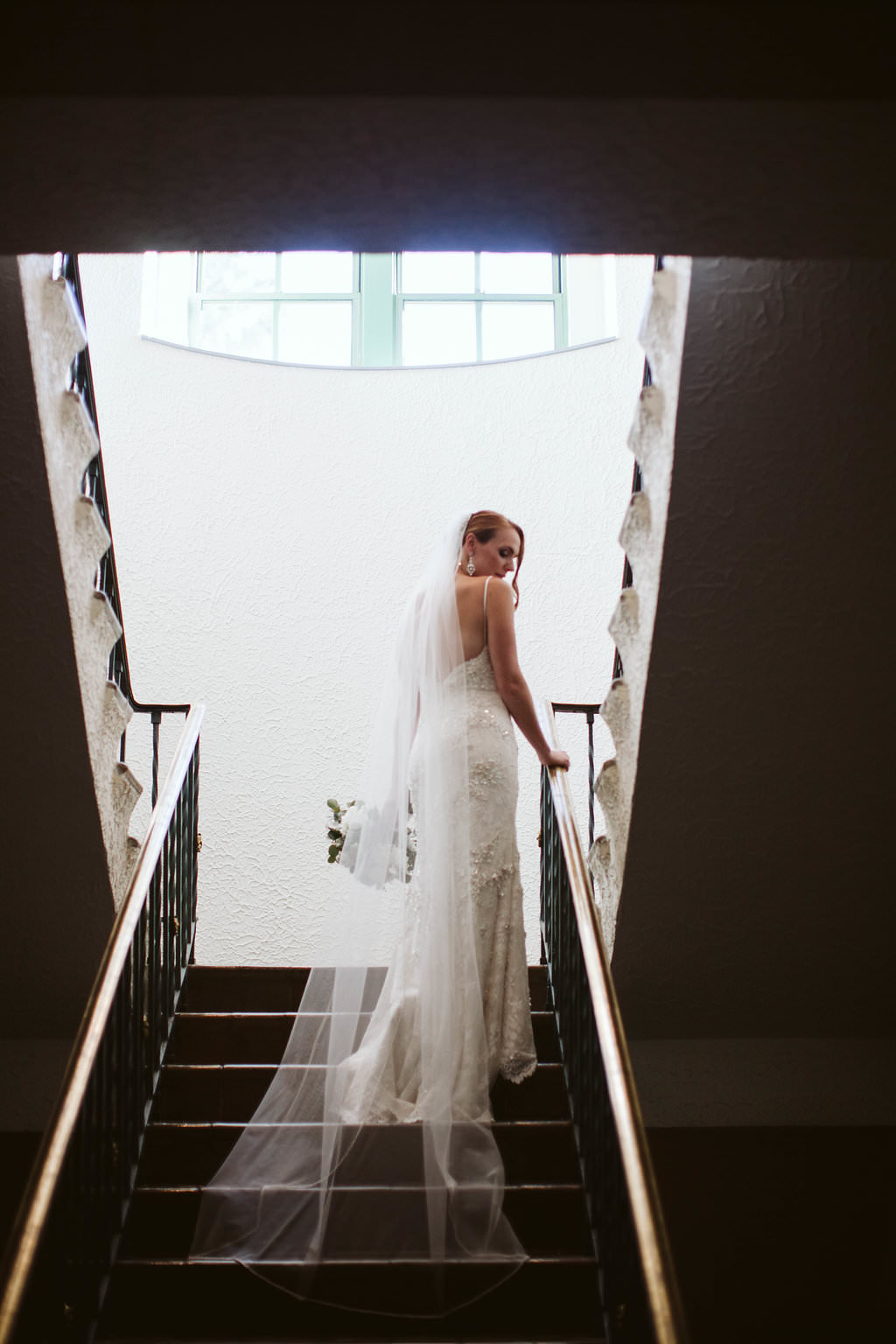 Brides in lace wedding dress and chapel veil on stairs