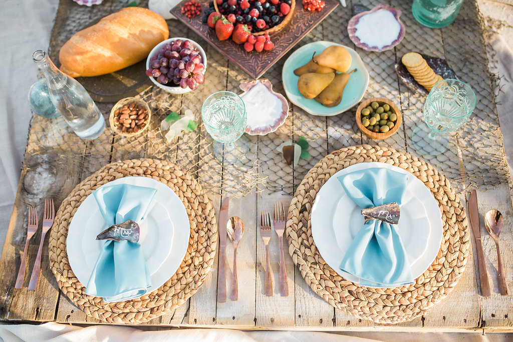 Florida Beach Inspired Wedding Styled Shoot, Natural Jute Braided Charger, White China Dishes, Light Blue Linens, Seashell Place Cards, Rose Gold Silverware, Fruit Platters and Aqua Crystal Glasses with Fishing Net Table Runner | Tampa Bay Wedding Planner UNIQUE Weddings and Events | Rentals Over the Top Linen Rentals
