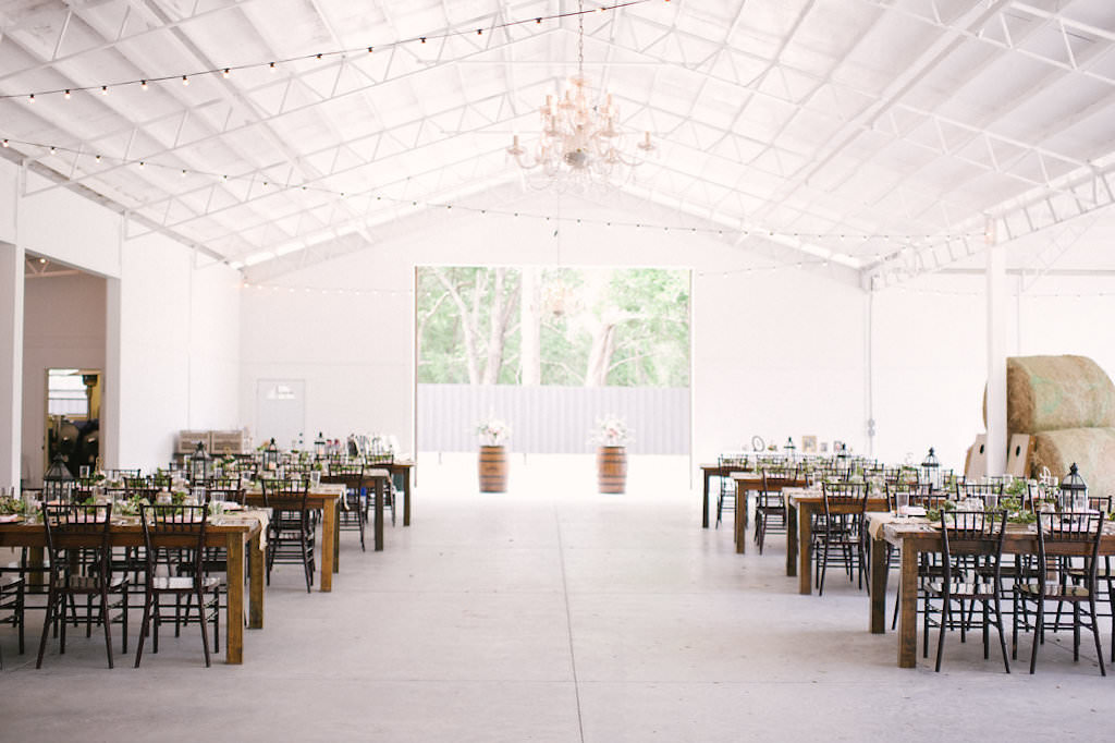 Florida Rustic Wedding Reception Decor, Long Wooden Tables, Black Chiavari Chairs, Wooden Barrels with Floral Arrangements, Hanging Bistro Lights | Inverness Wedding Venue Lakeside Ranch