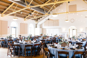 Vintage Rustic Whimsical Inspired Wedding Reception Decor, Round Tables with Dusty Blue Tablecloths, Wooden Chiavari Chairs, Low Centerpieces, Hanging Lights | Tampa Bay Wedding Planner Love Lee Lane | Lakeland Wedding Venue Magnolia Building | Rentals A Chair Affair