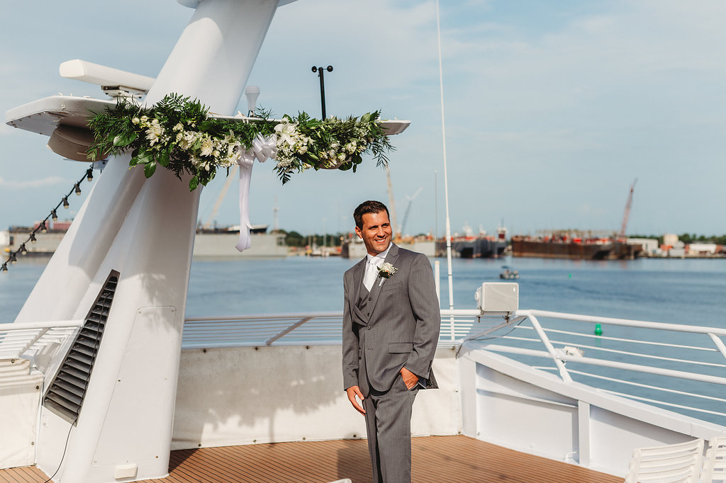 Florida Groom Waiting for Bride on Deck of Yacht in Grey Suit | Tampa Waterfront Wedding Venue Yacht Starship IV