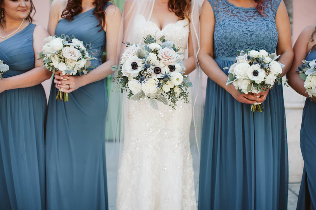 Bride with white anemone, rose and greenery wedding bouquet with bridesmaids in dusty blue long gowns