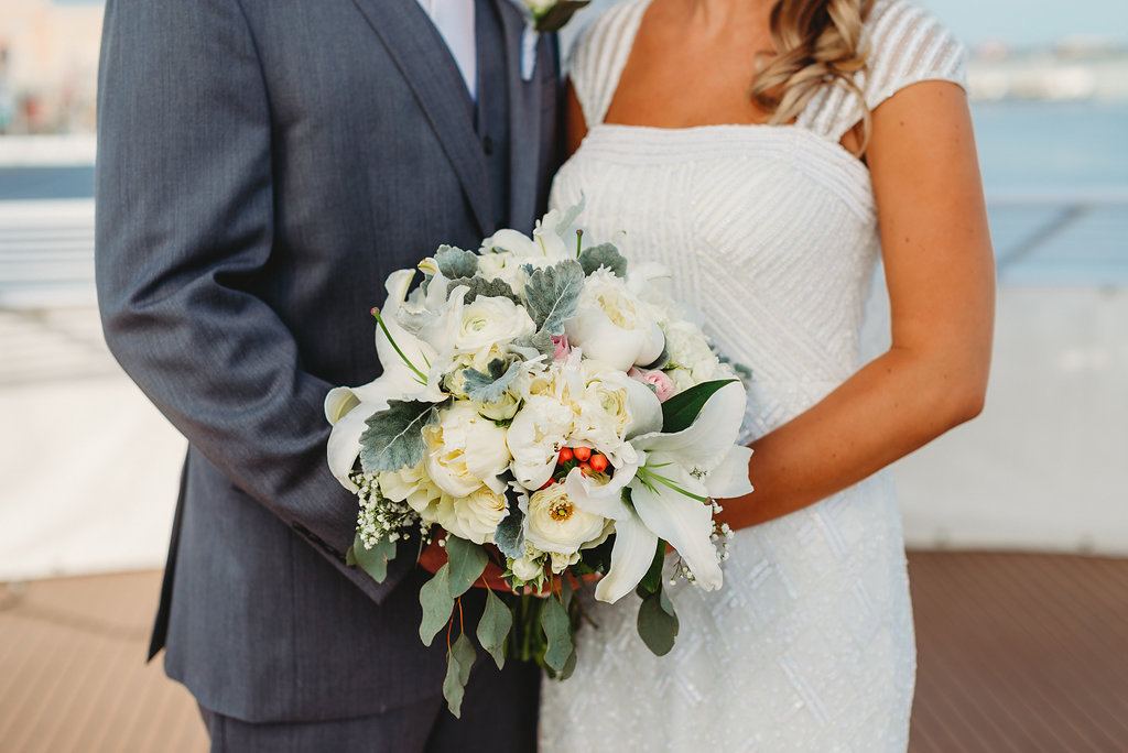 Florida Bride and Groom Wedding Portrait on Deck of Yacht, Bride in Scoop Neck Cap Sleeve Wedding Dress with Greenery, and White, Ivory, Blush Pink and Berries Floral Bouquet, Groom in Grey Suit | Tampa Waterfront Wedding Venue Yacht Starship IV