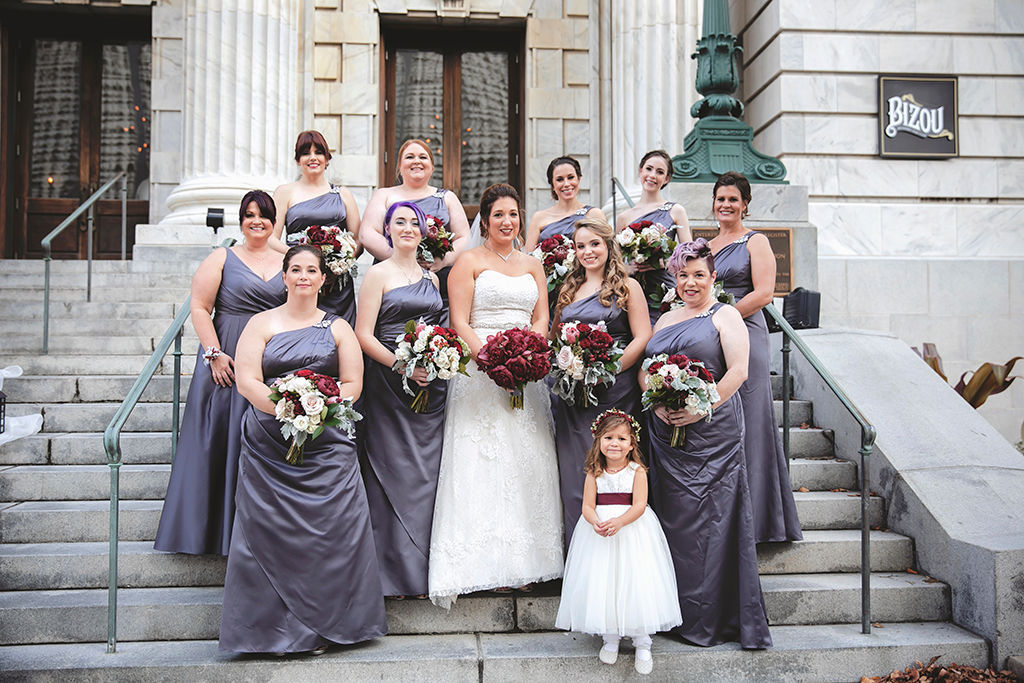 Tampa Bay Bride and Bridesmaids Wedding Portrait on Stairs of Downtown Tampa Wedding Venue Le Meridien, Bridesmaids in Matching Grey Silk One Strap Dresses, Bride in Strapless Sweetheart Lace and Rhinestone Belt Ballgown Wedding Dress with Dark Red, Burgundy Floral Bouquet, Flower Girl in White Dress with Burgundy Sash | Hair and Makeup LDM Beauty Group