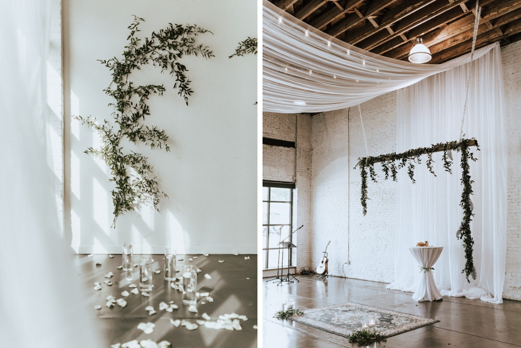 Romantic Wedding Ceremony Decor, Greenery Leaves on Wall, Glass Cylinder Floating Candles, White Drapery, Greenery Garland Arch, White Lanterns and White Flower Petals Down Ceremony Aisle | Lakeland Industrial Wedding Venue HAUS 820