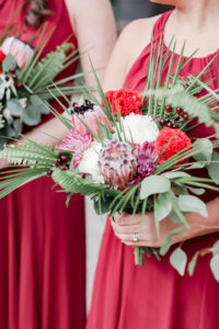 Bridesmaids in Long Red Dresses with Tropical Inspired Purple, Red, White, Pink, Silver Dollar Eucalyptus, Palm Tree Leaves, Greenery Floral Bouquet | Tampa Bay Wedding Photographer Lifelong Photography Studio