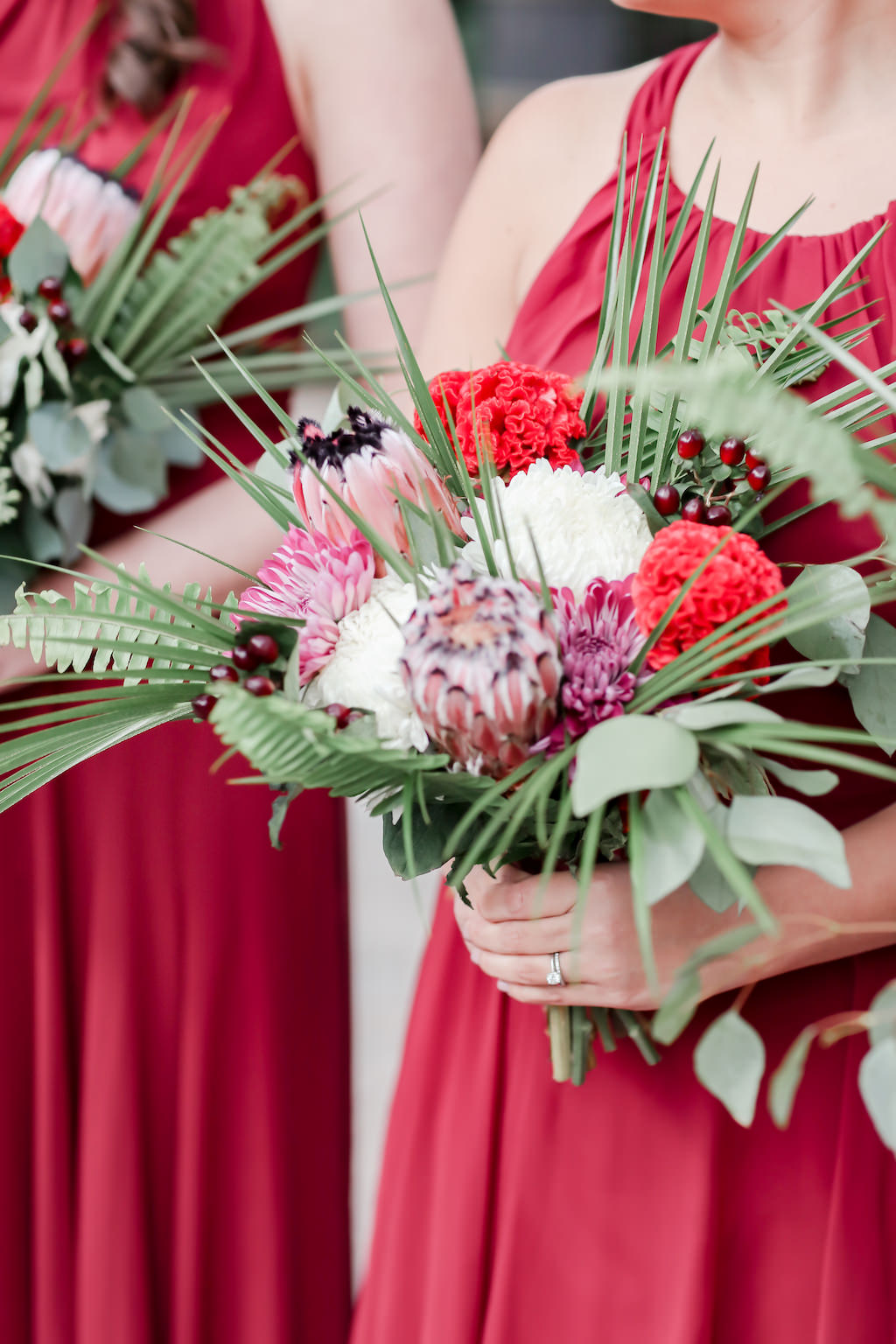 Bridesmaids in Long Red Dresses with Tropical Inspired Purple, Red, White, Pink, Silver Dollar Eucalyptus, Palm Tree Leaves, Greenery Floral Bouquet | Tampa Bay Wedding Photographer Lifelong Photography Studio