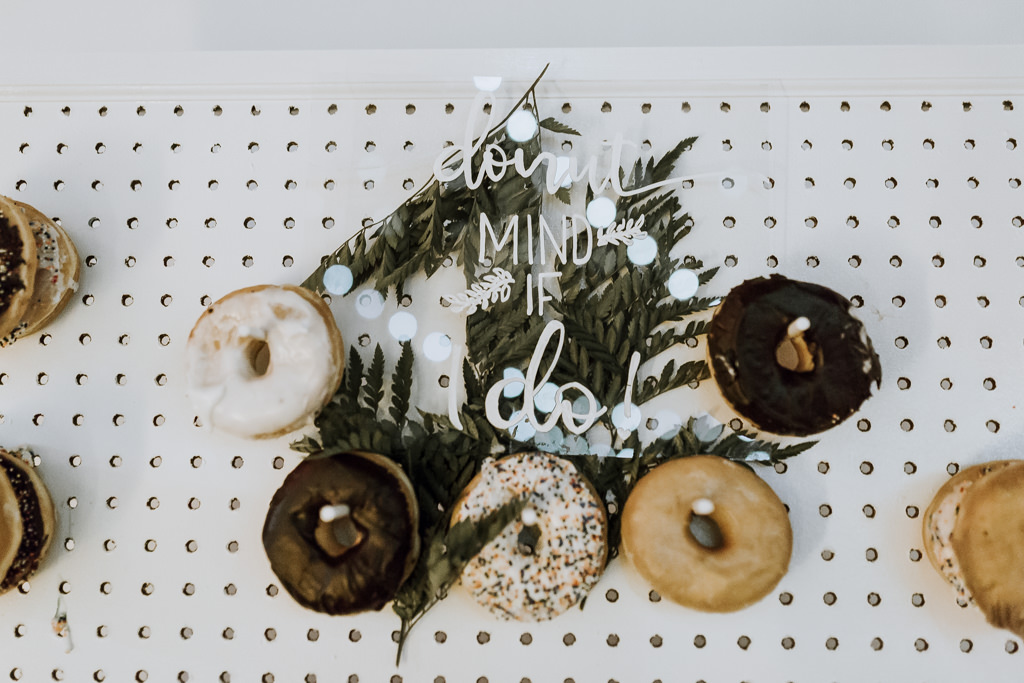 Wedding Reception Dessert Wall of Donuts, Clear Acrylic Sign and Green Leaves