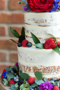 Two Tier Rustic Semi Naked Wedding Cake with Red, Purple, Pink, Blue and Greenery Real Flower Decor | Tampa Bay Wedding Photographer Caroline and Evan Photography | Florist Monarch Events and Design | Designer and Planner Southern Glam Weddings and Events | Cake Baker Artistic Whisk