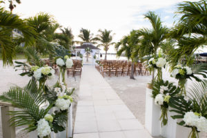 Beachfront Wedding Ceremony Decor, White Pillars with White Hydrangeas and Palm Tree Branches, Wooden Folding Chairs | St. Petersburg Waterfront Wedding Venue with Private Beach Isla Del Sol Yacht and Country Club