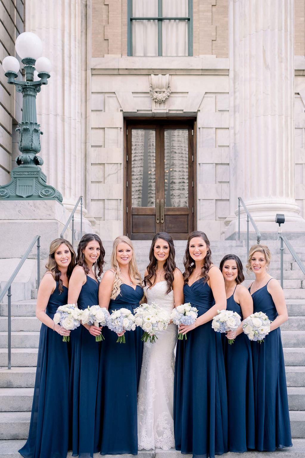 Florida Bride and Bridesmaids Bridal Party Wedding Portrait at Downtown Tampa Hotel Venue Le Meridien, Bridesmaids in Matching Navy Blue Dresses with White, Ivory and Pale Blue Floral Bouquets | Tampa Bay Wedding Planner Breezin Entertainment